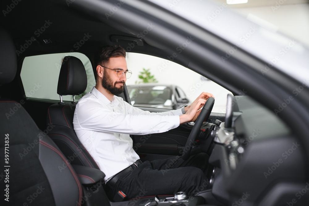 Happy young guy checking new luxury car, buying automobile at dealership centre. Portrait of cheerful millennial Caucasian man examining auto at showroom store Happy young guy checking new luxury car, buying automobile at dealership centre. Portrait of cheerful millennial Caucasian man examining auto at showroom store