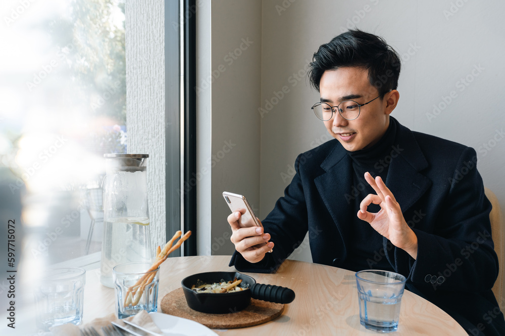 Asian businessman is using mobile phone in the restaurant. Asian businessman is using mobile phone in the restaurant.