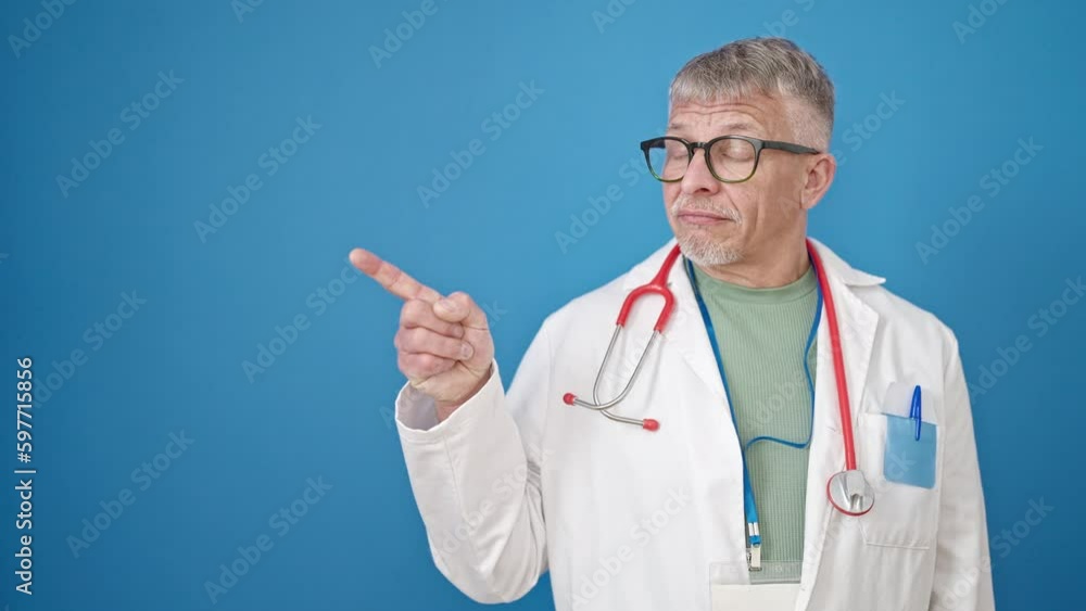 Middle age grey-haired man doctor smiling confident pointing with fingers to the side over isolated blue background Middle age grey-haired man doctor smiling confident pointing with fingers to the side over isolated blue background