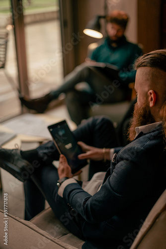 Long haired and bearded man working on the tablet. Close up shot