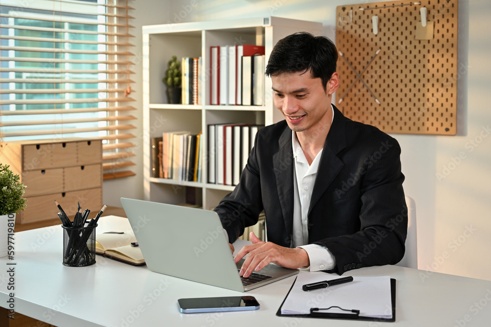 Obraz premium Photo of smiling adult male manager typing business email on laptop computer. Business and technology concept