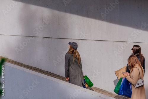 A side view photo of three stylish girls walking into a shopping center