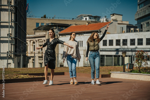 Three girls walking, singing and dancing from happiness. Careless girls on a beautiful sunny day