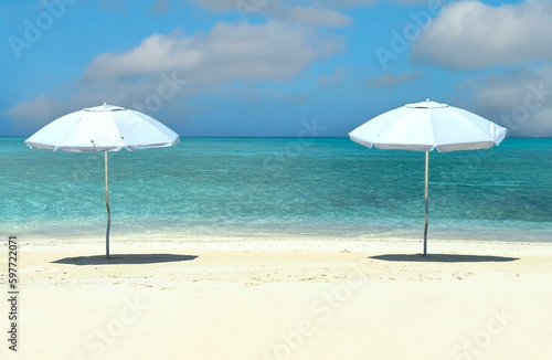 Summer tropical with white umbrella on the beach with  blue sky background © SASITHORN