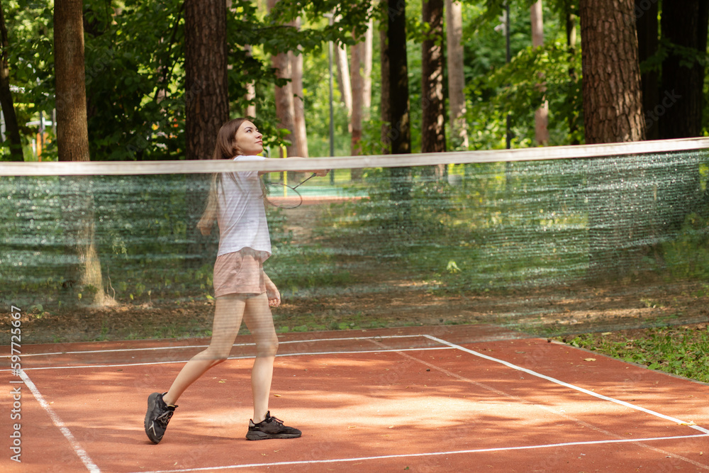 teenager sport outdoor, a girl with a racket plays badminton in the summer in a park in nature