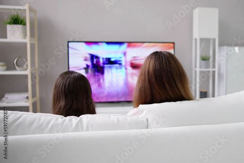 Smiling Mother And Daughter Watching Television