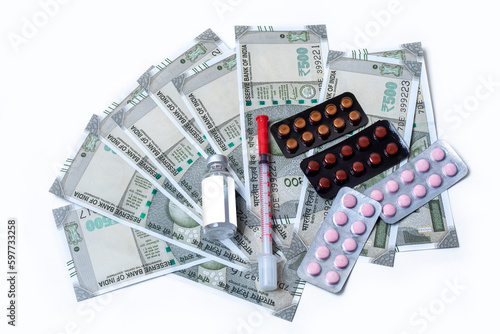 Medical concept. pills and syringe and medicine vial over indian banknotes on white background with copy space.