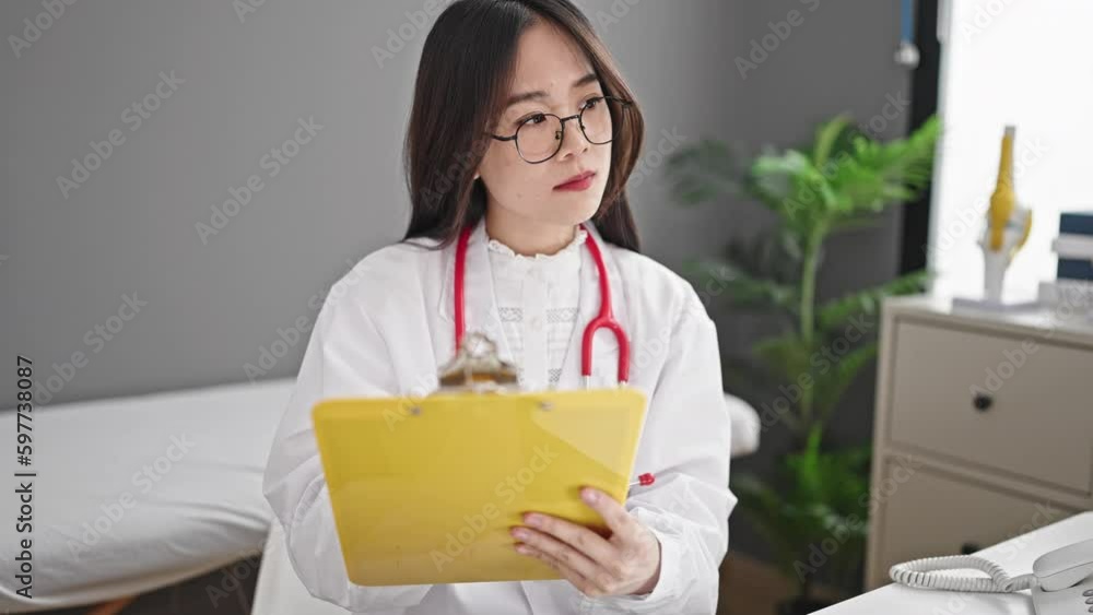 Young chinese woman doctor writing medical report at clinic Young chinese woman doctor writing medical report at clinic
