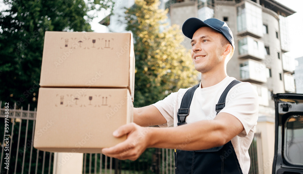 The man is a satisfied employee of the courier company delivering the order to customers in a cardboard box. The man is a satisfied employee of the courier company delivering the order to customers in a cardboard box.
