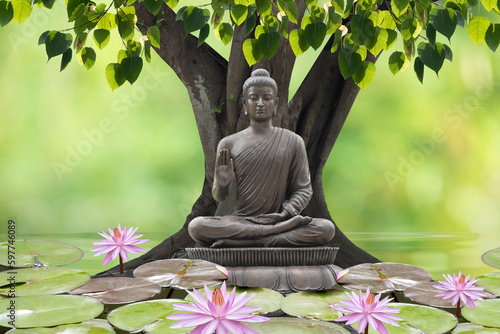 Buddha statue sitting under the bodhi tree on nature background. photo
