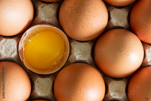 Chicken eggs lie in a tray on the kitchen surface with a broken yellow yolk. Buying products and goods in the store.