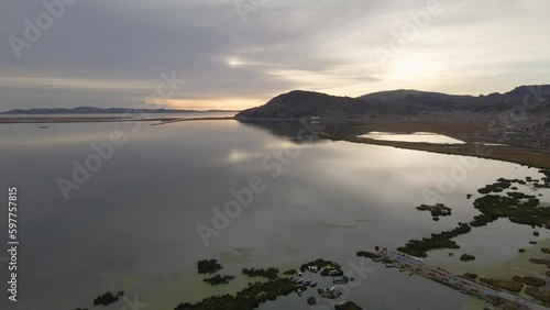 4K Aerial Drone Orbit Arc over Lake Titicaca and Puno, Peru. City, boats, and mountains visible.