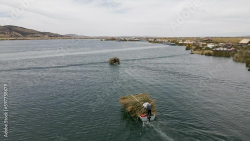 4K Aerial Drone follows three boats carrying reeds at Uros Islands in Lake Titicaca, Puno, Peru. Authentic Boat, Lake, Reeds, Floating Islands visible