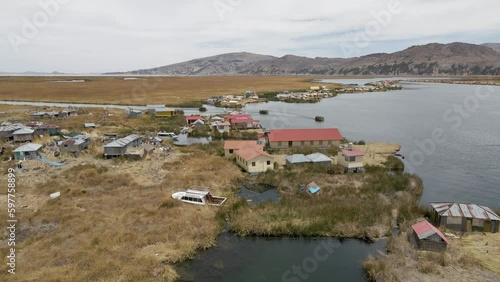 4K Aerial Drone view Uros Islands and boat carrying reeds at Lake Titicaca, Puno, Peru. Authentic Boat, Lake, Reeds, Floating Islands visible.