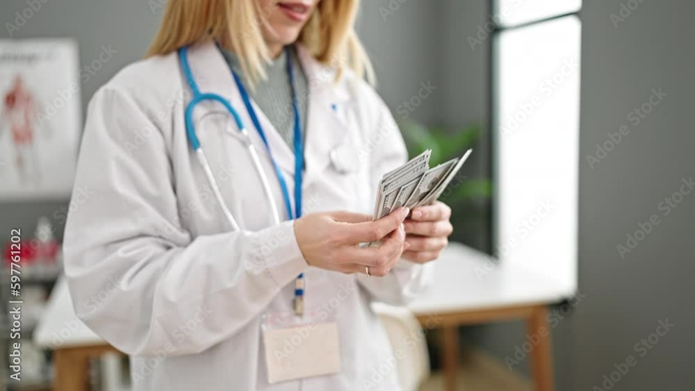 Young blonde woman doctor smiling confident counting dollars at clinic Young blonde woman doctor smiling confident counting dollars at clinic