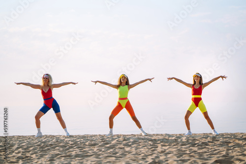 Young dancers in colorful swimsuits are dancing in the morning. Сoncept of sports, fitness, aerobics. Active sport.