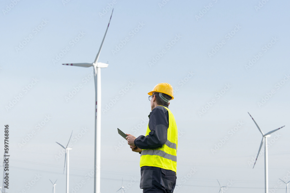 Engineer with tablet computer on a background of wind turbines Engineer with tablet computer on a background of wind turbines