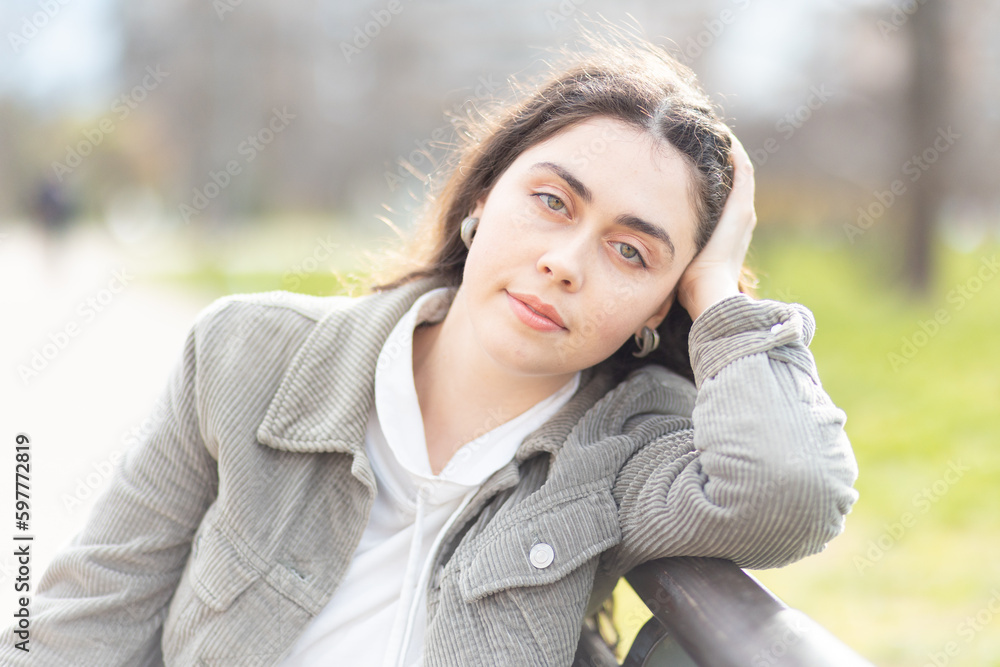 Portrait of dreamy beautiful Caucasian woman wearing jacket posing in park. Concept of carefree and psychology