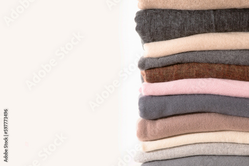 Pile of knitted cashmere on white background. Folded autumn and winter clothing.