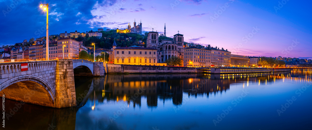Lyon city skyline at night, over the Pont Bonaparte Bridge, vibrant water reflections on the Saone River, Saint George Church, and La Basilique Notre Dame de Fourvière in France
