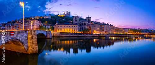 Lyon city skyline at night, over the Pont Bonaparte Bridge, vibrant water reflections on the Saone River, Saint George Church, and La Basilique Notre Dame de Fourvière in France