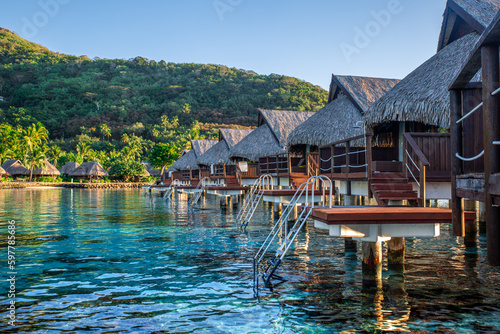 Bungalow sur l'eau en Polynésie française avec une eau turquoise et du corails. Lieu de tourisme paradisiaque.