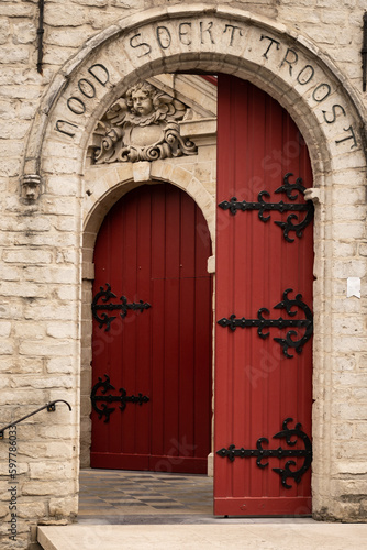 red wooden open entrance to basilica church courtyard Carmelite convent vilvoorde. religious building troostkerk is Our Lady of Consolation with historic architecture © drew