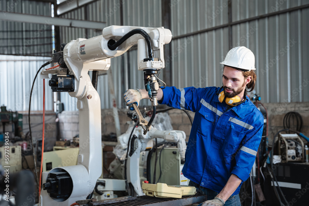 Industrial engineers are controlling the automated robot arms machine welding steel welding robots in industrial manufacturing factory.