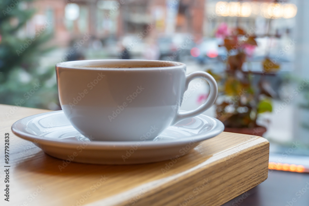 Tasty raf coffee in restaurant on city life background. Still life white cup with hot drink on wooden platform. Coffee steamed and whipped cream with crushed chocolate. Relaxation on terrace in cafe Tasty raf coffee in restaurant on city life background. Still life white cup with hot drink on wooden platform. Coffee steamed and whipped cream with crushed chocolate. Relaxation on terrace in cafe