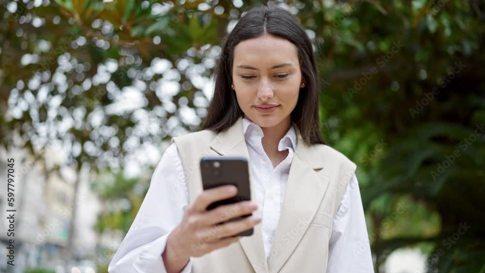 Young beautiful hispanic woman using smartphone with serious expression at park Young beautiful hispanic woman using smartphone with serious expression at park