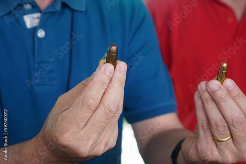 A shooting instructor is comparing 9mm and 11mm handgun ammunition in hand.