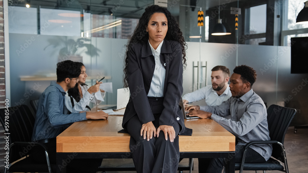 Worried upset leader woman tired worker businesswoman sitting on table in conference room sad with business problem failure multicultural team diverse colleagues in background discussing work project Worried upset leader woman tired worker businesswoman sitting on table in conference room sad with business problem failure multicultural team diverse colleagues in background discussing work project