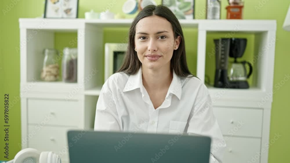 Young beautiful hispanic woman using laptop sitting on table at dinning room Young beautiful hispanic woman using laptop sitting on table at dinning room