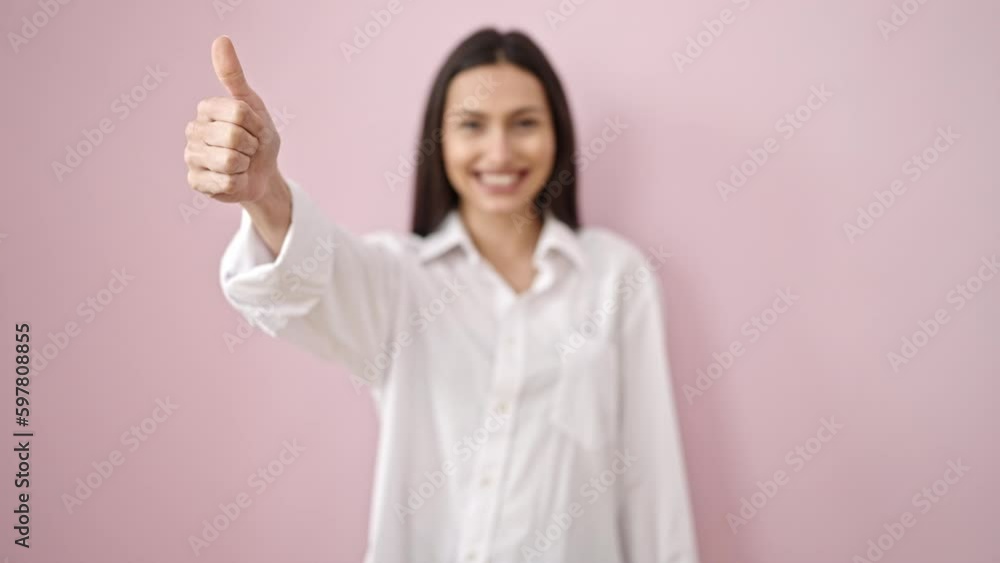 Young beautiful hispanic woman smiling confident doing ok sign with thumb up over isolated pink background Young beautiful hispanic woman smiling confident doing ok sign with thumb up over isolated pink background