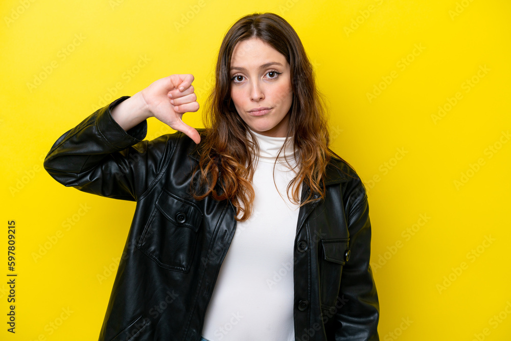 Young caucasian woman isolated on yellow background showing thumb down with negative expression Young caucasian woman isolated on yellow background showing thumb down with negative expression