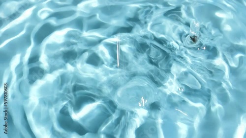 Video of water splashes and falling drops on a blue background. Water drop splash blue colored.