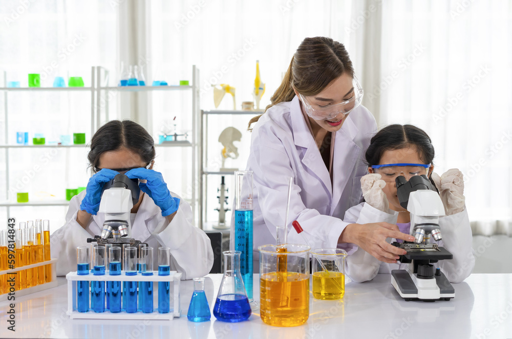 female scientist as a mentor is teaching the students, kids studying science in laboratory female scientist as a mentor is teaching the students, kids studying science in laboratory