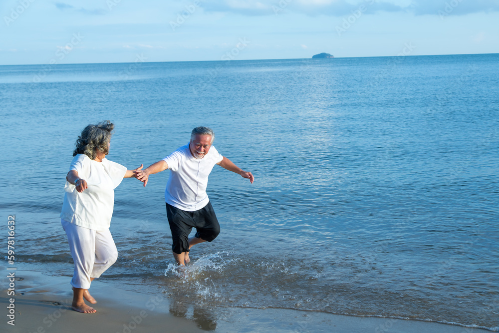 Elderly couple. Joyful nice elderly couple smiling and happy running on the beach