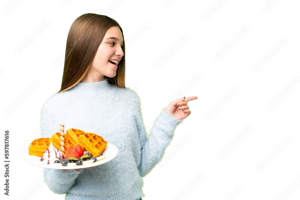 Teenager girl holding waffles over isolated chroma key background pointing finger to the side and presenting a product Teenager girl holding waffles over isolated chroma key background pointing finger to the side and presenting a product