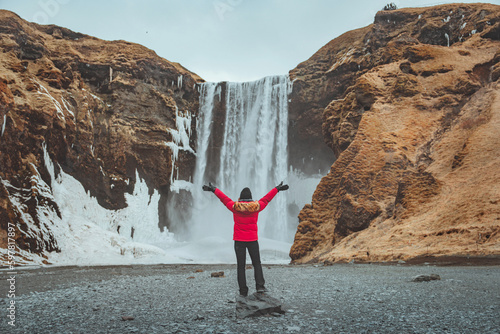 Tableau sur toile Happy tourist traveler woman enjoying with open arms on Skogafoss waterfall in I