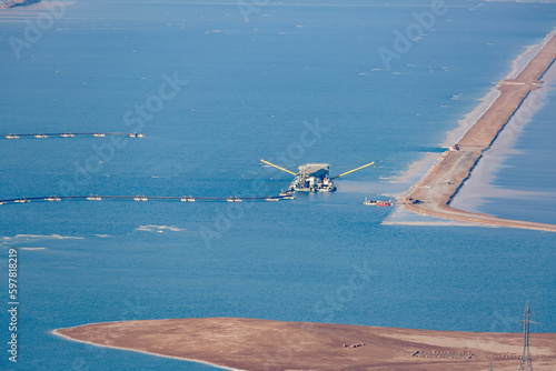 Pontoon mining potash and mud from the Dead Sea. Industrial facilities, sea landscape. Salt extraction, production facility region in Israel. Coast Dead Sea white salt crystals beach, clear water. photo