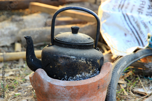 Billede på lærred black old kettle been used for a long time on a small brown furnace