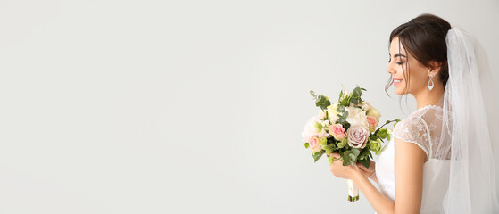 Beautiful young bride with bouquet of flowers on light background with space for text