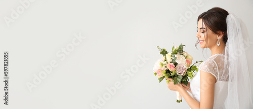 Photo Beautiful young bride with bouquet of flowers on light background with space for