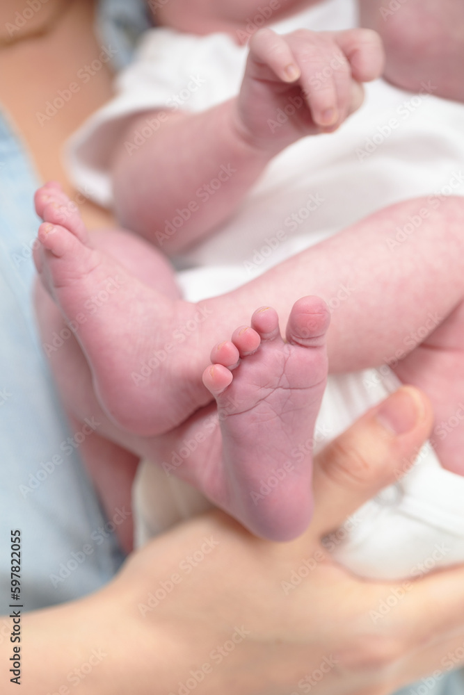 HOUSTON, TEXAS - APRIL 26TH 2023: a newborn baby’s tiny pink feet are photographed close up in their mother’s hands to compare the size. You can see every detail and line on the skin. HOUSTON, TEXAS - APRIL 26TH 2023: a newborn baby’s tiny pink feet are photographed close up in their mother’s hands to compare the size. You can see every detail and line on the skin.