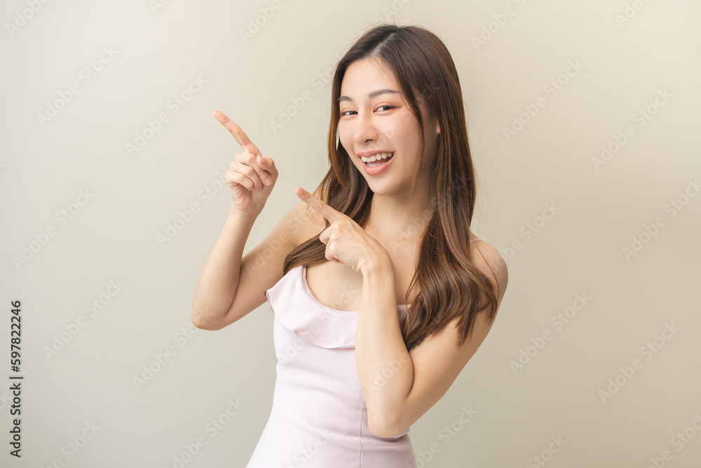 Smiling positive, attractive asian young woman, girl pointing finger, wearing beautiful pink dress with female brunette long hair feeling happy looking at camera standing isolated on white background Smiling positive, attractive asian young woman, girl pointing finger, wearing beautiful pink dress with female brunette long hair feeling happy looking at camera standing isolated on white background