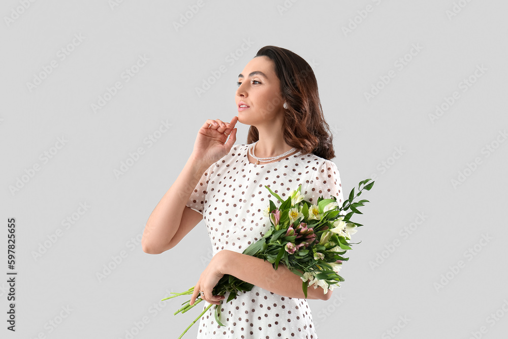 Young woman in dress with alstroemeria flowers on grey background Young woman in dress with alstroemeria flowers on grey background