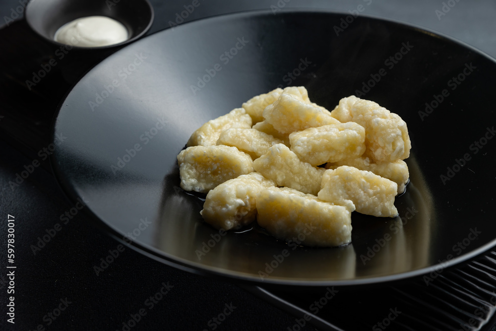 A bowl of gnocchi with a side of sour cream. A bowl of gnocchi with a side of sour cream.