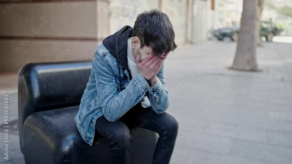 Young hispanic man stressed sitting on a bench at street Young hispanic man stressed sitting on a bench at street