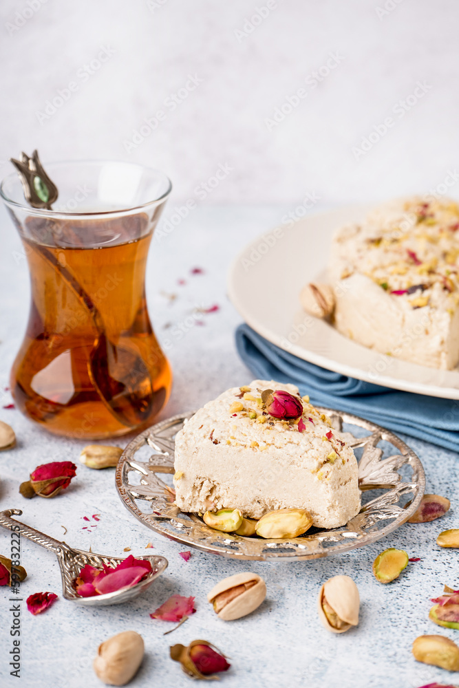 Plates with tasty Tahini halva and glass of Turkish tea on light background Plates with tasty Tahini halva and glass of Turkish tea on light background